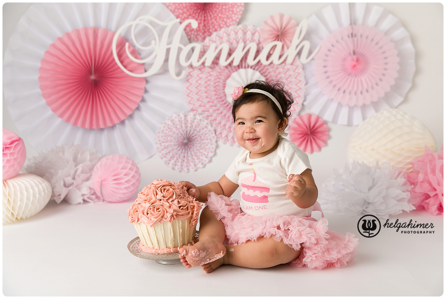 cake smash session for a chines little girl in pink, the background have pinwheels and she is wearing a pink tutu